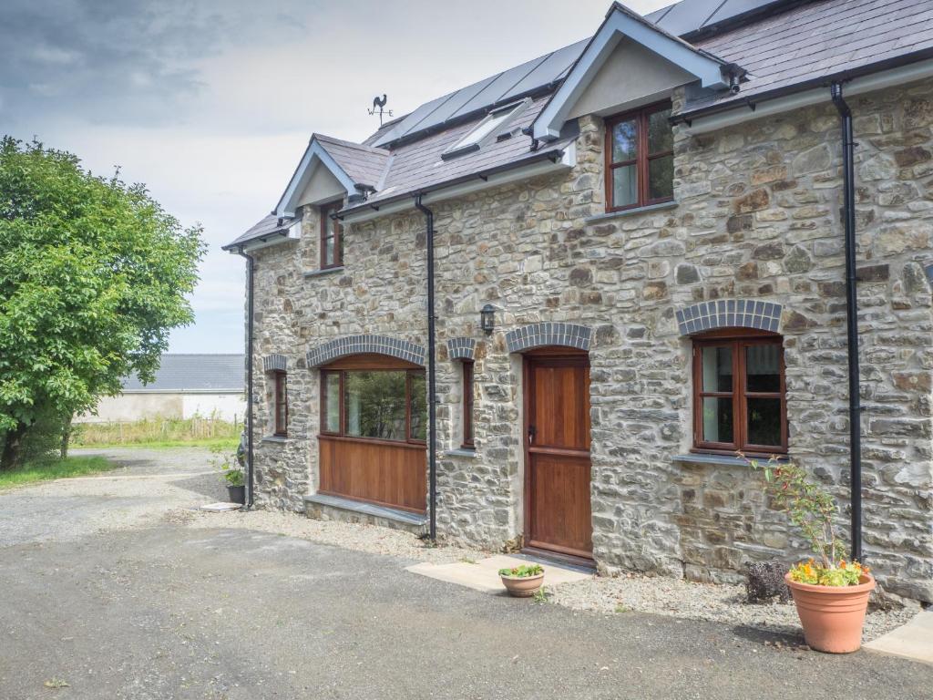 a stone house with wooden doors and windows at Ty Ceiniog New Quay in Cross Inn