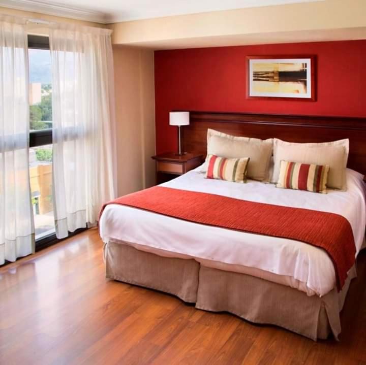 a bedroom with a large bed with a red wall at DEPARTAMENTO ESTUDIO (HOTEL PREMIUM TOWER SUITES) in San Luis