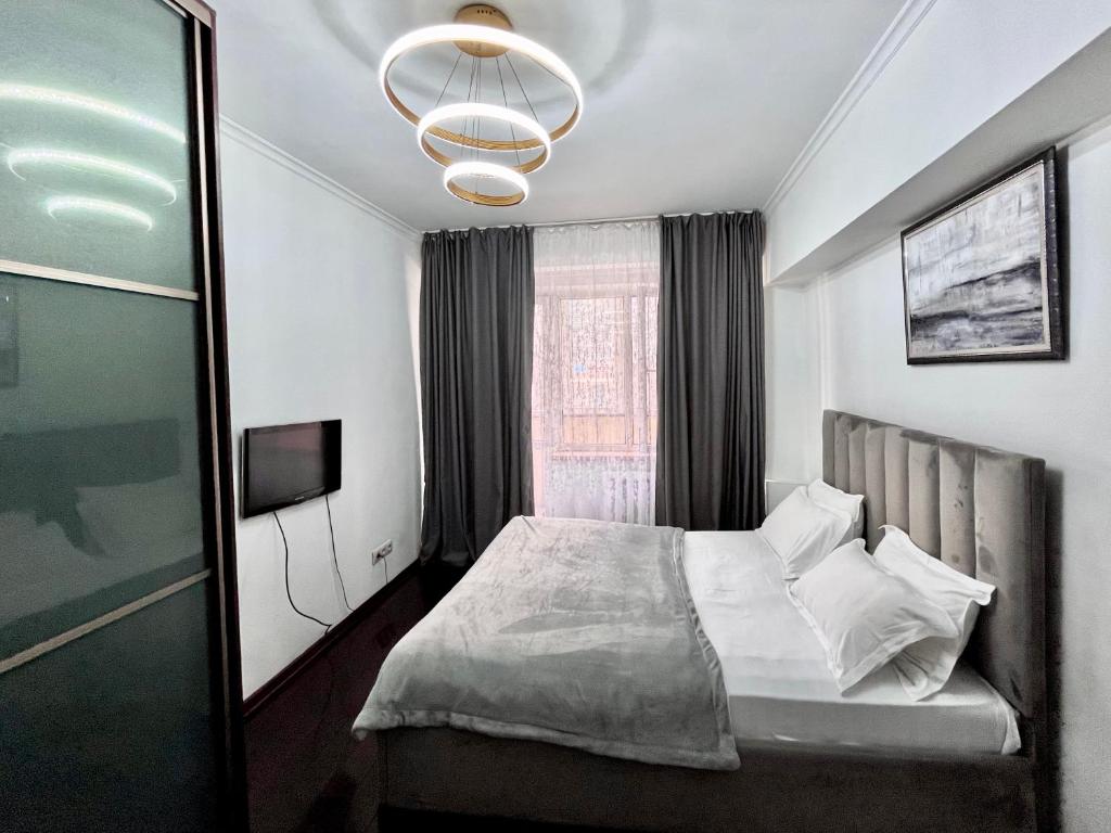 Schlafzimmer mit einem Bett, einem Fenster und einem Kronleuchter in der Unterkunft Great location Arbat, Zhibek zholy 81 & drinking water in Almaty