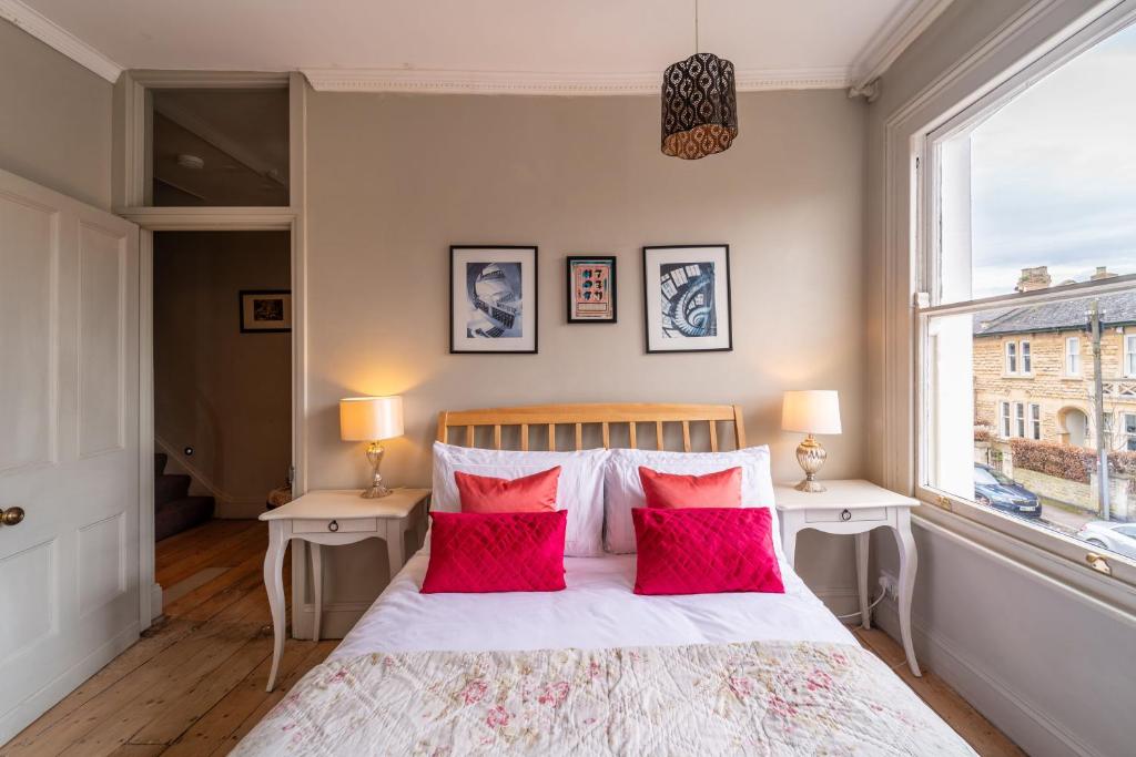 a bedroom with a bed with red pillows and a window at Victorian Townhouse 5 bedrooms Cheltenham in Cheltenham