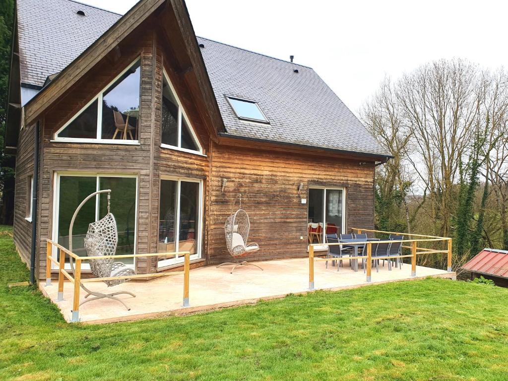 een huis met een terras met stoelen erop bij La Maison Verte in Clécy