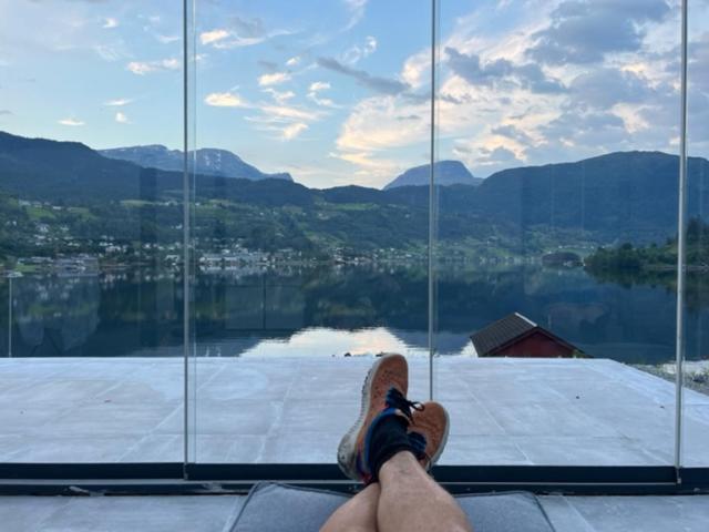 a person with their feet up on a window looking outside at Trolltun, Frystevegen 4 in Ulvik