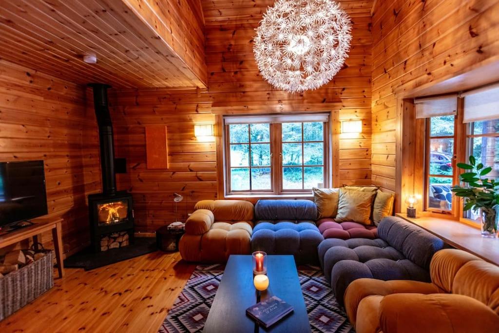 una sala de estar con sofás y una lámpara de araña. en Large Luxury Log Cabin Getaway, en Ballyconnell