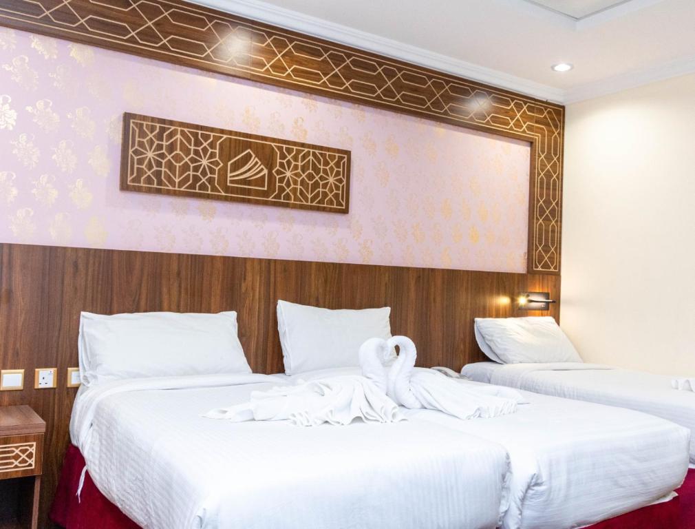two beds in a hotel room with white sheets at Mahd Al Reasala Hotel 1 - فندق مهد الرسالة 1 in Al Khansāk