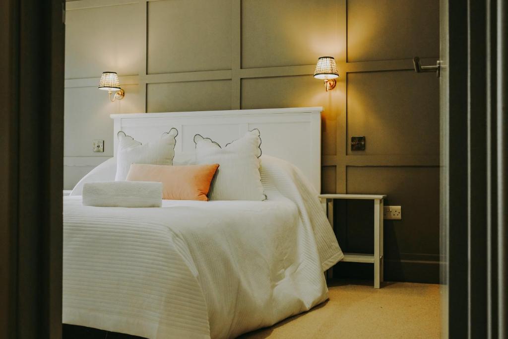 um quarto com uma cama branca e uma almofada laranja em Number 1 Cannons at The Old Dairy Clevedon em Clevedon