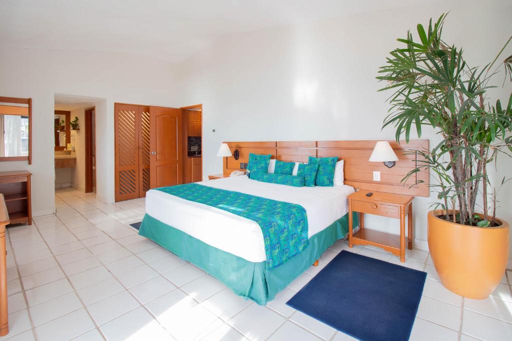 Plaza Pelicanos Club Beach Resort All Inclusive في بويرتو فايارتا: غرفة نوم بسرير كبير مع وسائد زرقاء