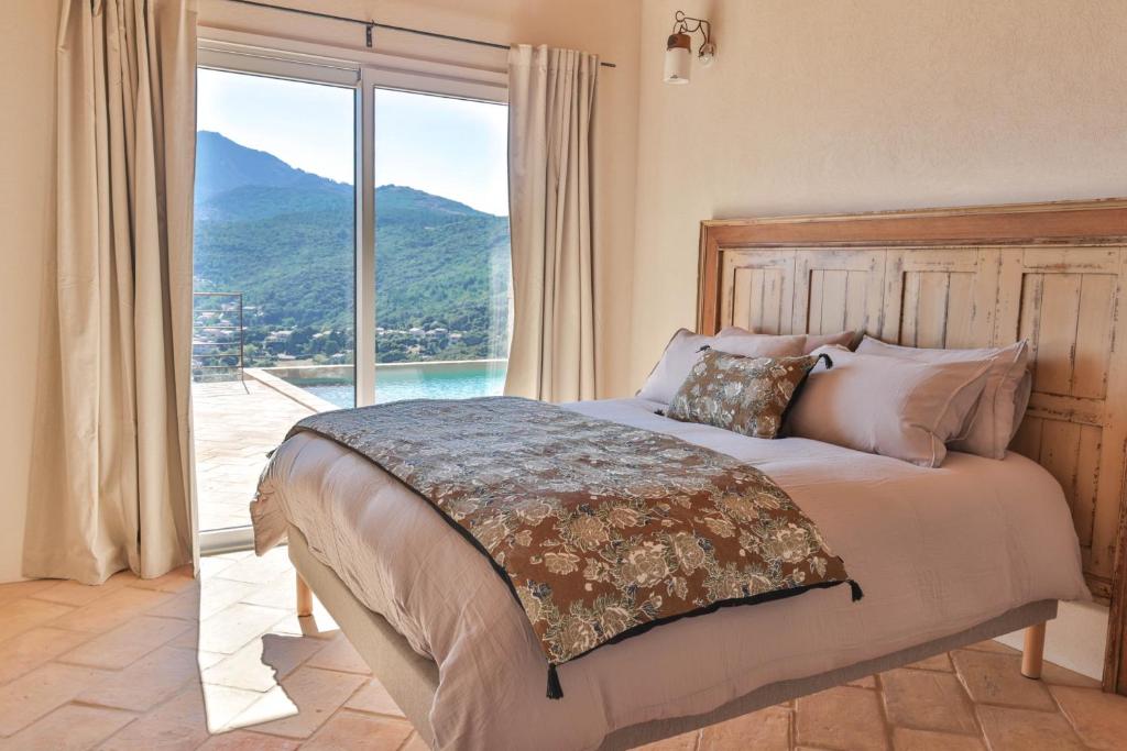 a bedroom with a bed with a view of a mountain at Les Demeures de Piana in Piana
