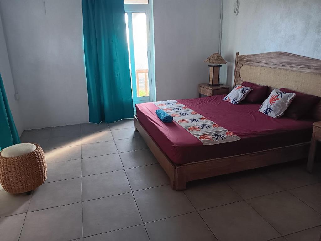Schlafzimmer mit einem Bett mit roter Bettwäsche und einem Fenster in der Unterkunft Le bijou chez laineda in Mt Bois Noir