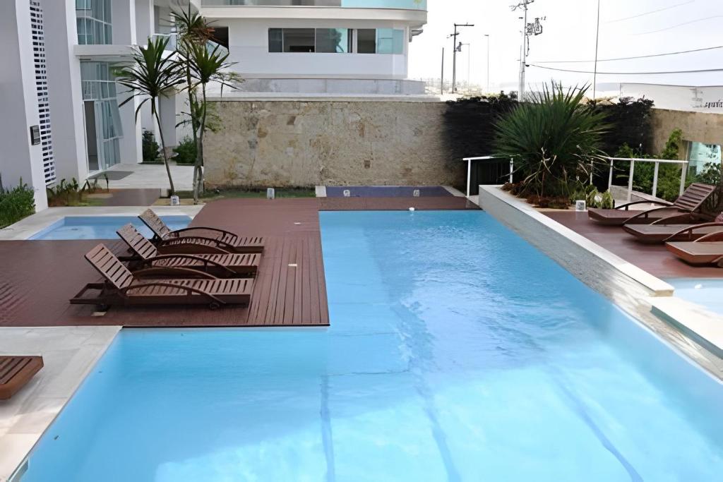 una piscina con tumbonas y una casa en FLAT MANDAI CABO FRIO en Cabo Frío