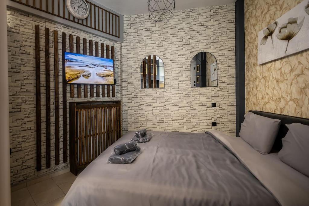 GpxClr GuestSuiteNo2 في لاريسا: غرفة نوم مع سرير كبير وتلفزيون على الحائط