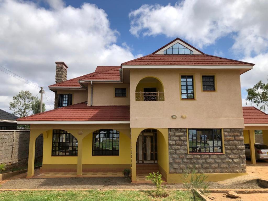 VILLA ESPERANZA KITUI في Kitui: منزل اصفر بسقف احمر