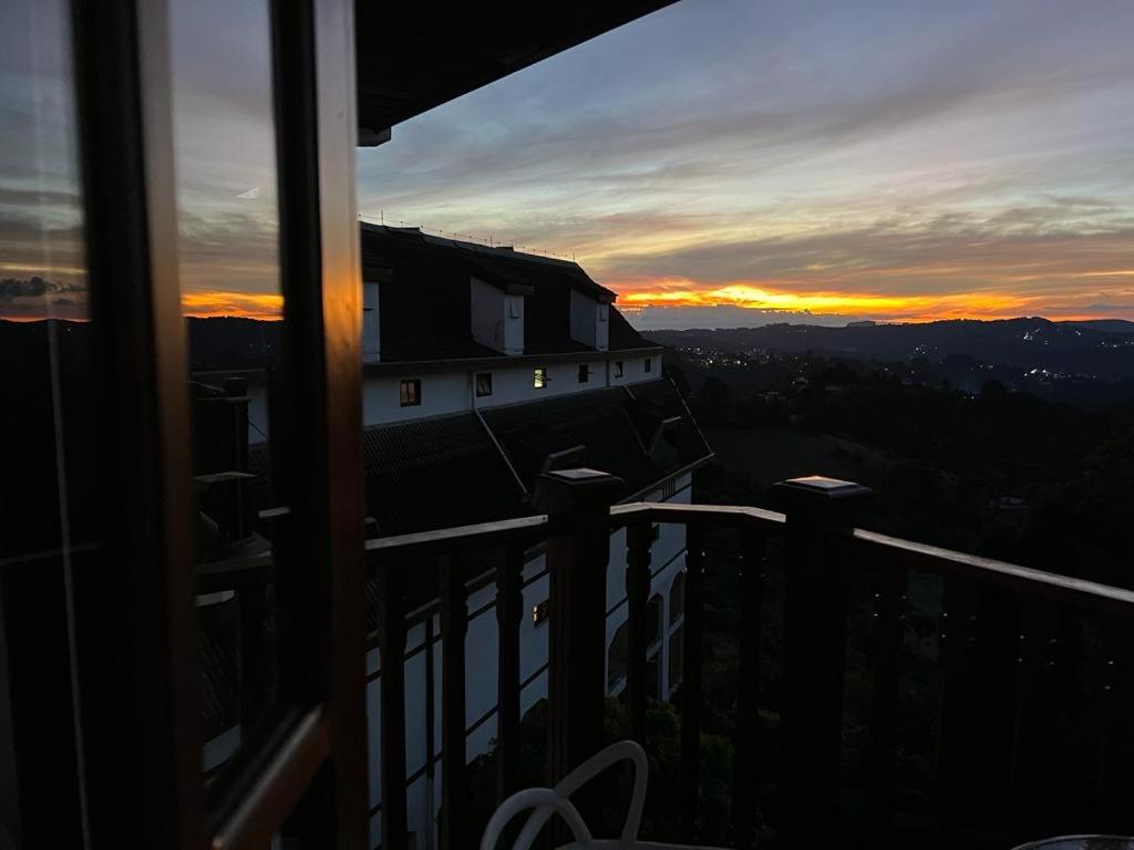 een balkon met uitzicht op de zonsondergang bij Suíte no castelo flat no Home Green Home in Campos do Jordão