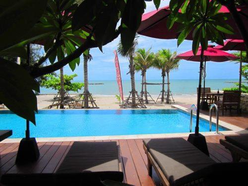 een zwembad met stoelen en parasols naast het strand bij Chidlom Resort in Haad Chao Samran