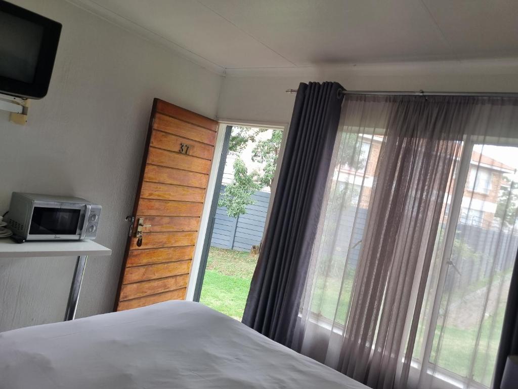 a bedroom with a bed and a large window at Palmar Hotel in Johannesburg