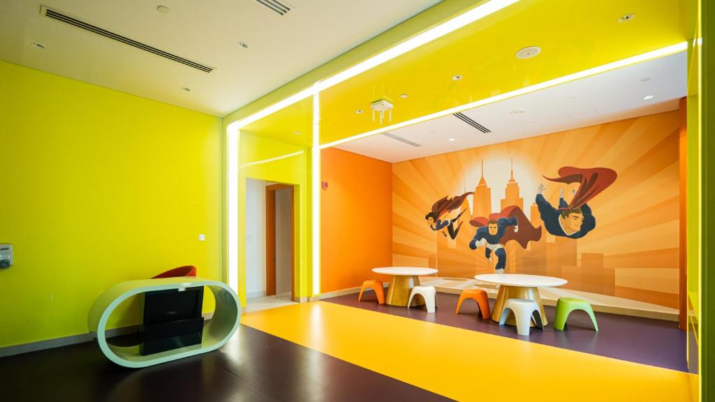 a yellow room with two tables and a tv at Livin' Holidays - Luxury studio with Bay view in Dubai