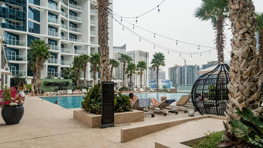 a pool at a resort with palm trees and buildings at Livin' Holidays - Luxury studio with Bay view in Dubai