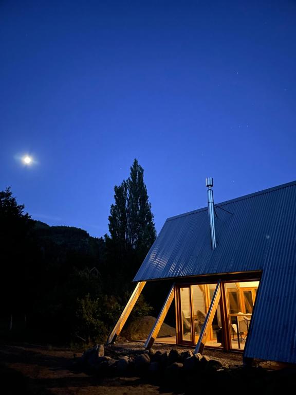 Cabaña con techo azul y ventanas por la noche en El Diucón Eco Lodge en Villa Meliquina