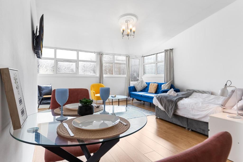 een woonkamer met een tafel en een bed bij Spacious Studio High Street Location in Londen