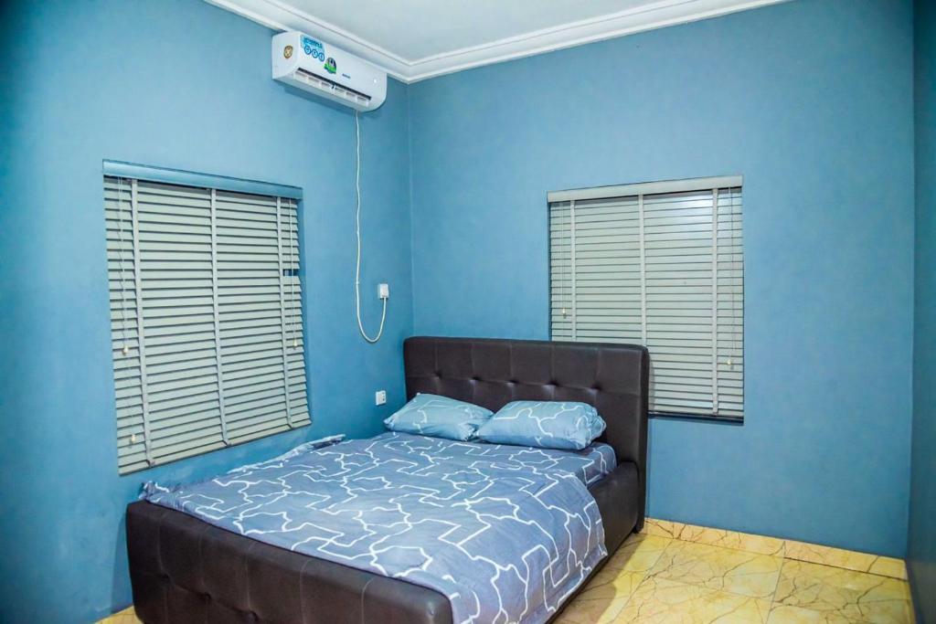 Schlafzimmer mit blauen Wänden und einem Bett mit blauer Bettwäsche in der Unterkunft Jimms Place in Owerri