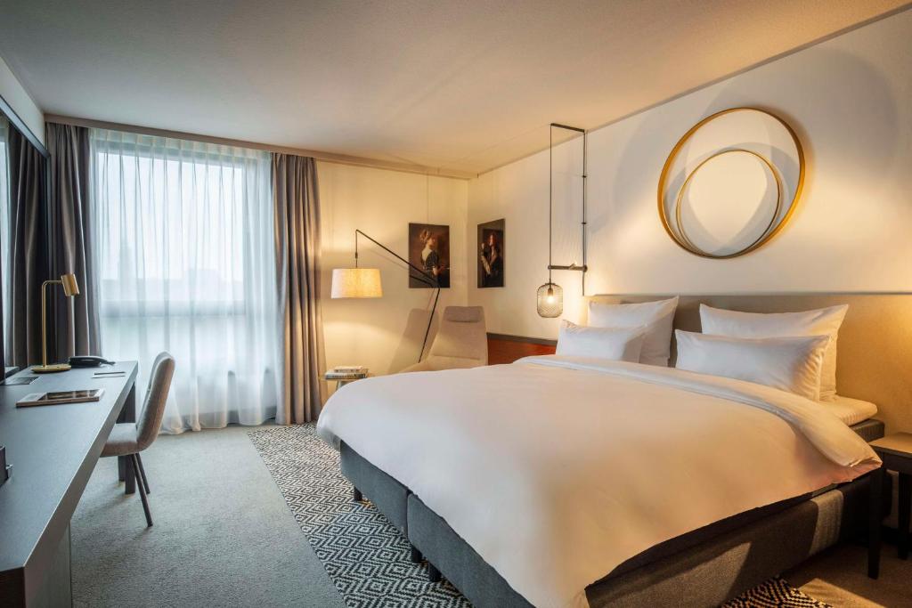 um quarto de hotel com uma cama grande e um espelho em Scandic Nürnberg Central em Nurembergue