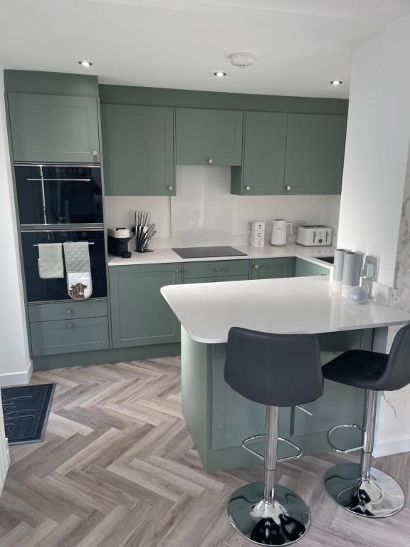 a kitchen with green cabinets and a table and chairs at Savannah Lodge in Wyke Regis