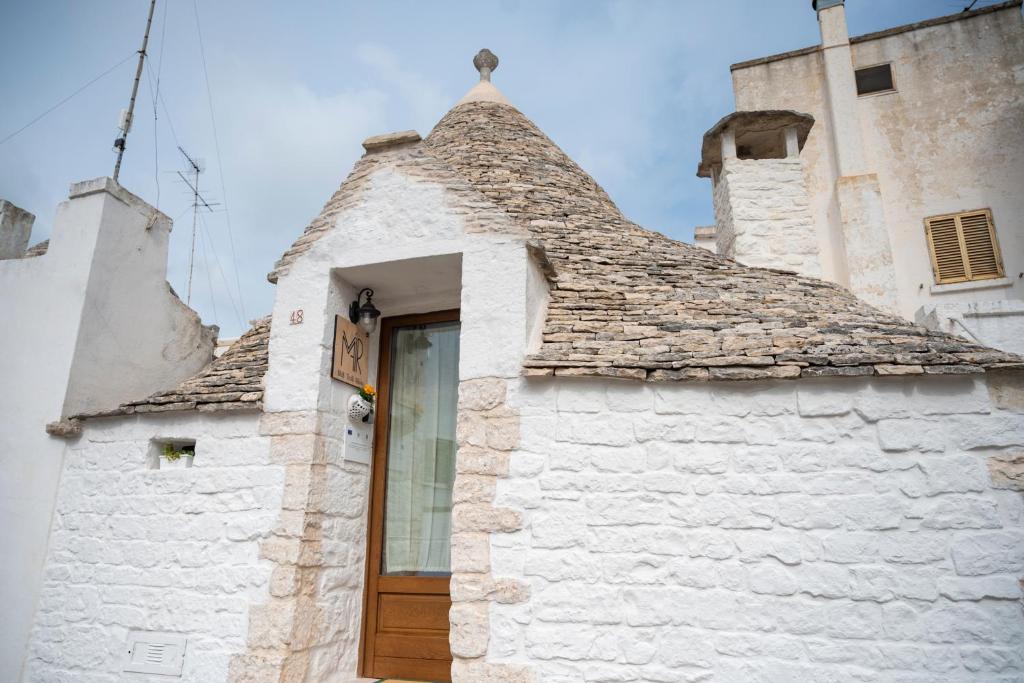 a white building with a roof with a wooden door at B&B TRULLI MIRIVA' in Alberobello