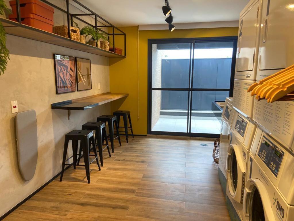 - un bar avec tabourets dans une cuisine aux murs jaunes dans l'établissement Studio Moderno em Pinheiros - 300m do Metrô e HC, à São Paulo