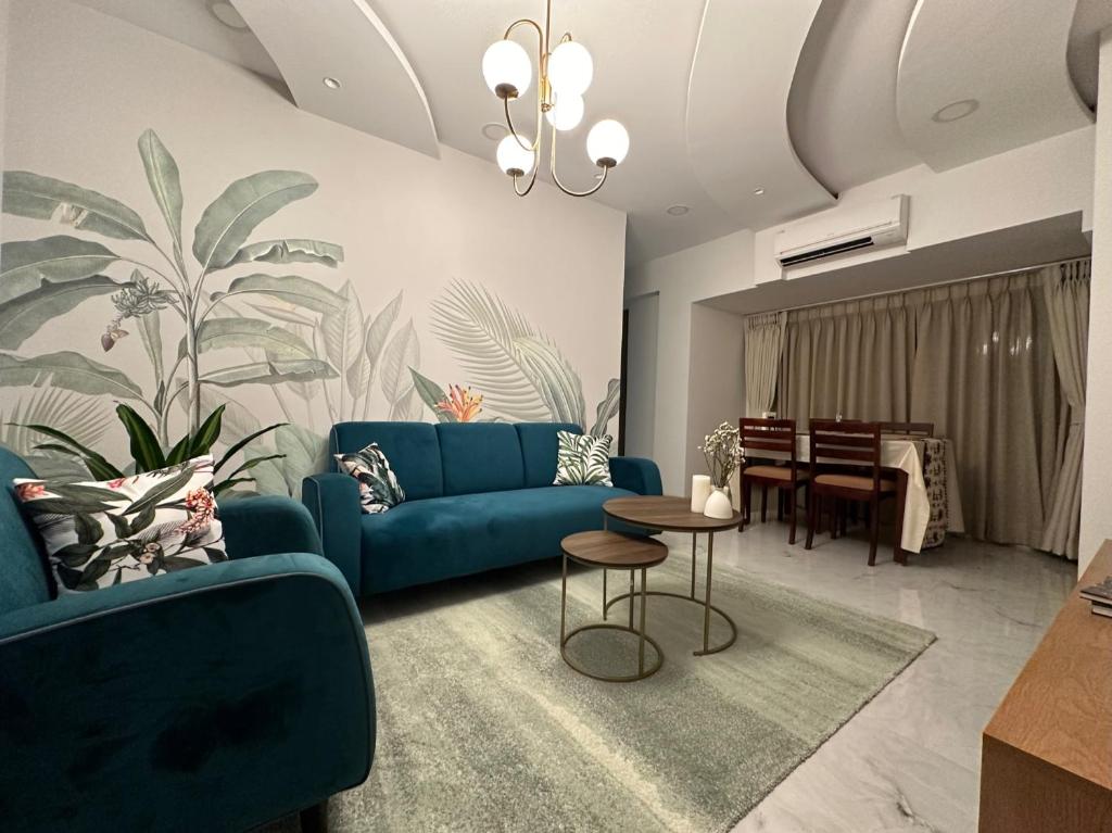 a living room with a blue couch and a table at Luxury 2 BHK Tropical Apartment in Khar West in Mumbai