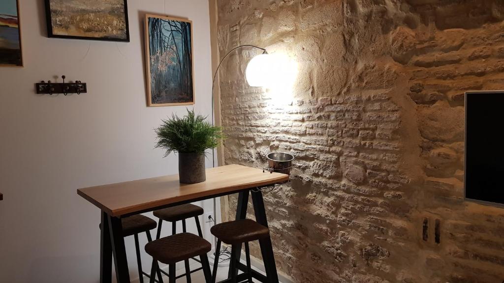 einen Tisch mit Hockern in einem Zimmer mit einer Steinmauer in der Unterkunft Loft en casco histórico La Pintora - Parking publico opcional in Jerez de la Frontera