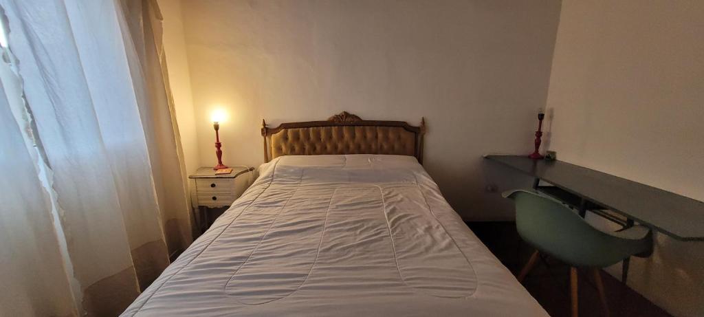 a small bedroom with a bed and a desk and a lamp at Casa Amor in Capilla del Monte