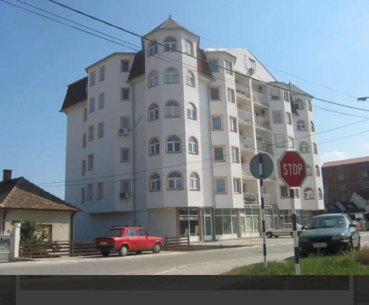 um carro vermelho estacionado em frente a um grande edifício em Apartman PRESSTIGE em Smederevska Palanka