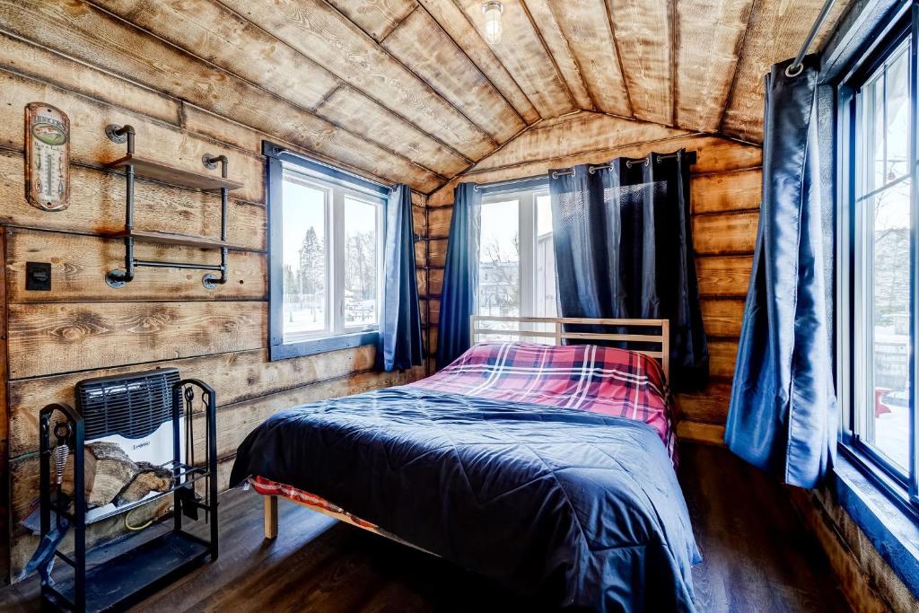 a bedroom with a bed in a log cabin at Your Cozy Cabin Retreat in Saint-Rémi-dʼAmherst