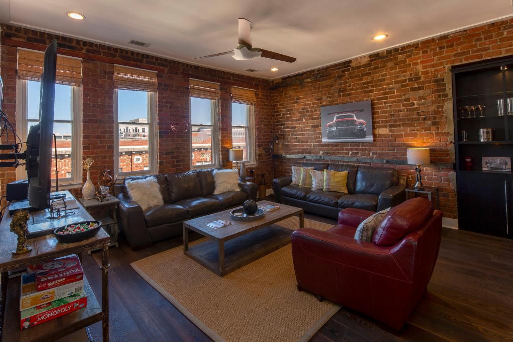 a living room with couches and a brick wall at Charming Savannah Penthouse: Grand Views & Dual Parking in Savannah