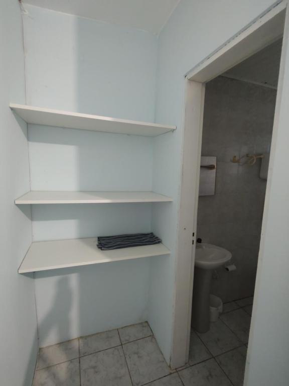 a bathroom with white shelves and a toilet at Pousada Golfinhos in Imbé