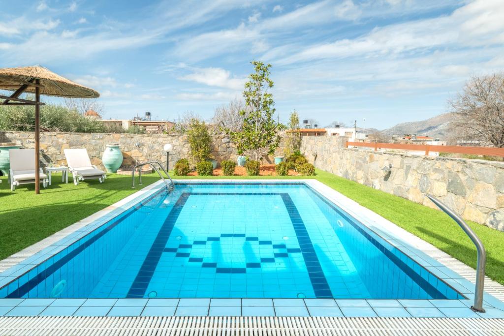 a swimming pool in a yard with a stone wall at Treasure of Herbs Complex in Panormos Rethymno