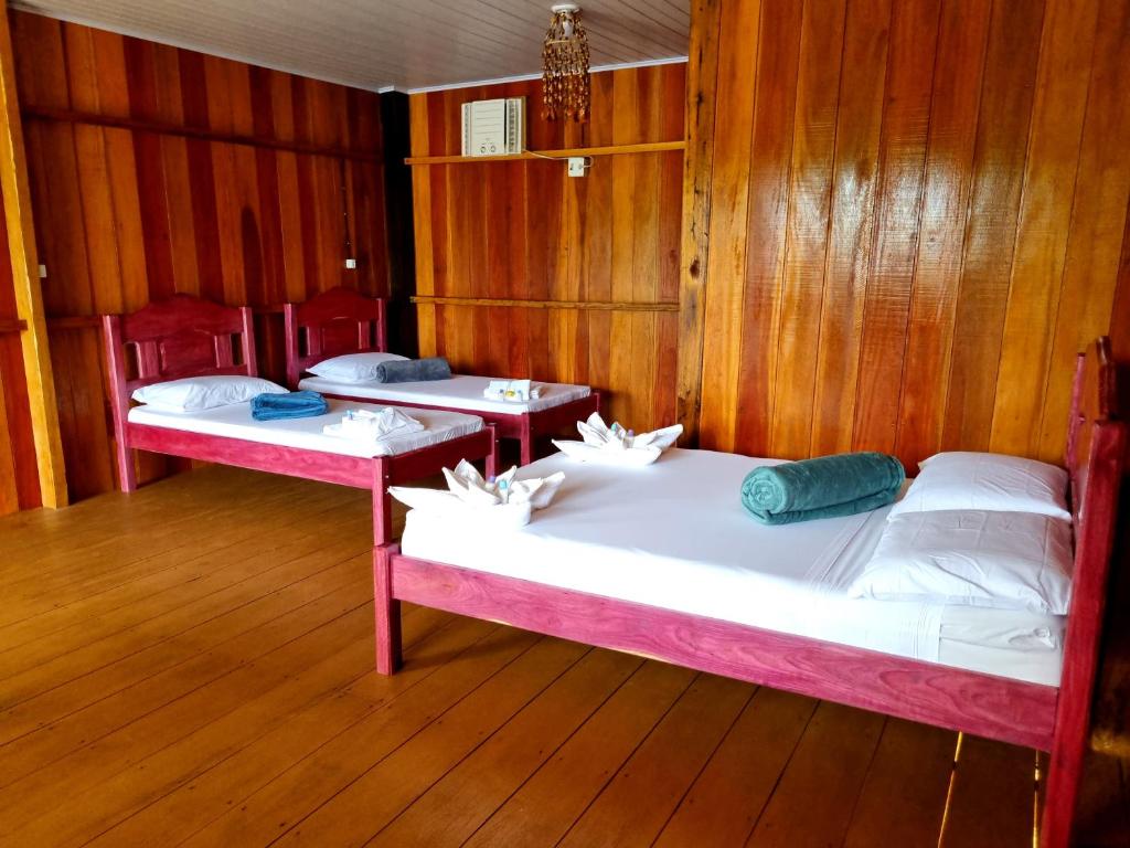 - 2 lits dans une chambre dotée de murs en bois dans l'établissement POUSADA DA DRI LODGE, à Iranduba