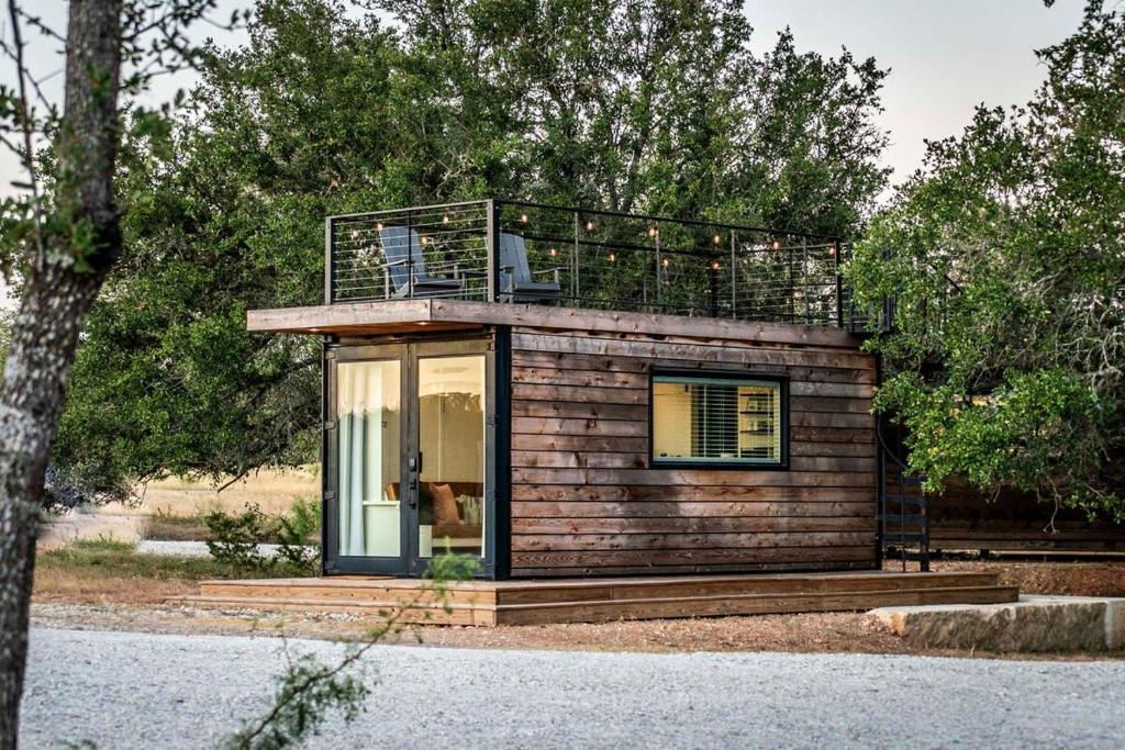 a small house with a balcony on top of it at New Oak Grove-Container Retreat in Fredericksburg