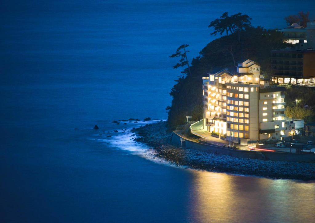 a building on a hill next to the ocean at night at Hamanoyu in Higashiizu