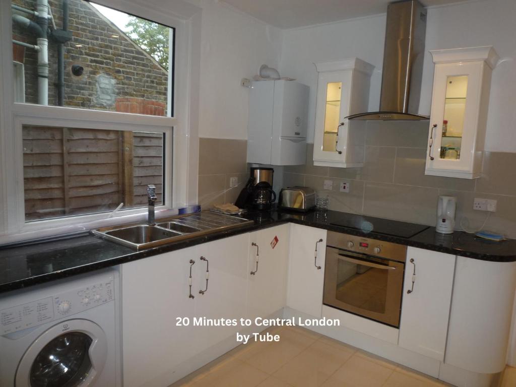 una cocina con armarios blancos y fregadero en Boundary Road, 1 Bedroom & 2 Bedroom Flats, en Londres
