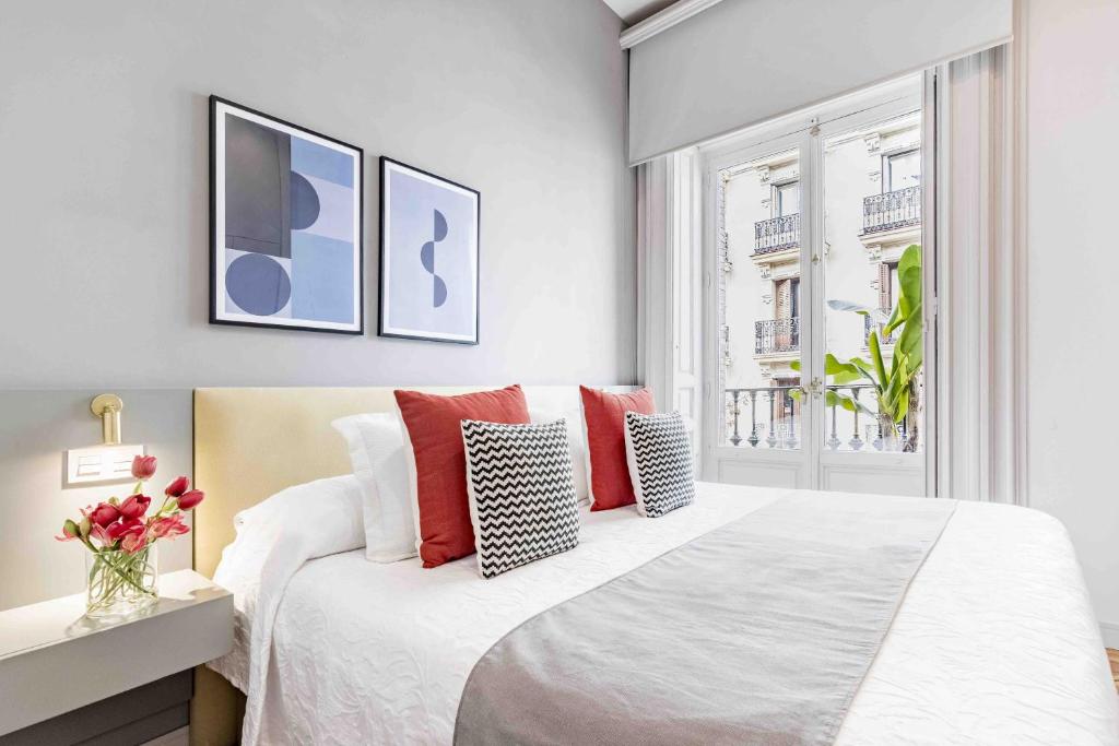 a white bedroom with a large bed with red pillows at Premium Belgravia Harrods Apartment in London