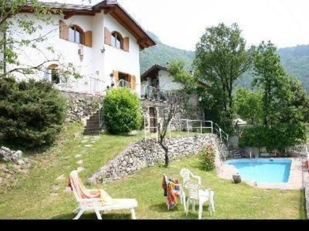 een huis met een tuin met stoelen en een zwembad bij Ferienhaus für 9 Personen ca 170 qm in Tenno, Gardasee Nordufer Gardasee in Tenno