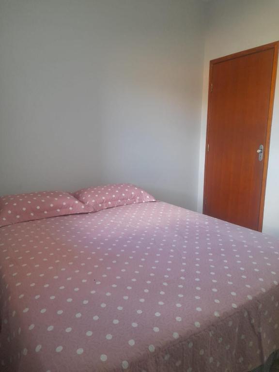 1 cama con colcha de lunares y armario de madera en Quarto para temporada, en Ribeirão Preto