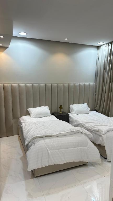 a bedroom with two beds and a wall at حي الورود مقابل برج الخرج in Al Kharj