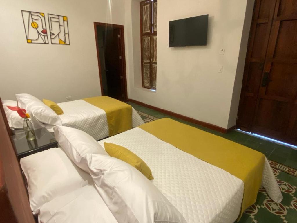 a hotel room with two beds and a television at Hotel Boutique Iyarí in Palmira