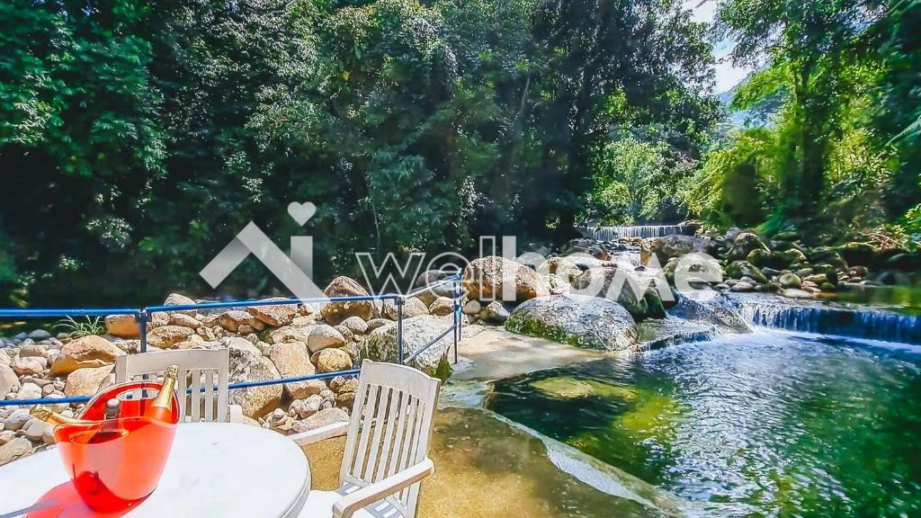 un parco acquatico con tavolo, sedie e cascata di Casa com piscina natural e lazer em Guapimirim a Guapimirim