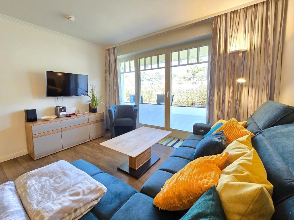 ein Wohnzimmer mit einem blauen Sofa und einem Tisch in der Unterkunft Dünenpark Binz - Komfortplus Ferienwohnung mit 2 Schlafzimmern und Terrasse im Erdgeschoss 166 in Binz