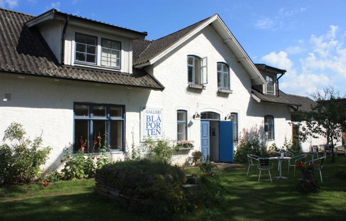 Una casa blanca con un cartel en la parte delantera. en Galleri Blå Porten, en Alby