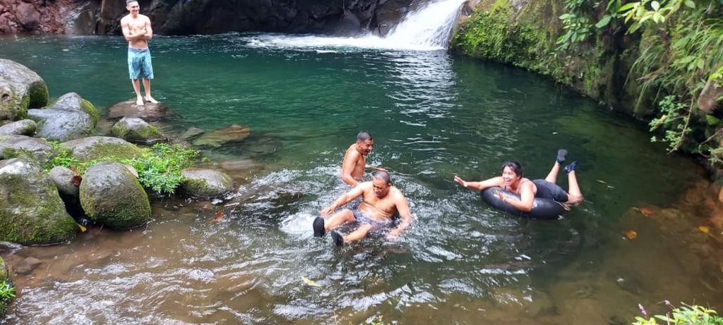 un grupo de personas en el agua cerca de una cascada en Pozas Guacimo, en Guápiles
