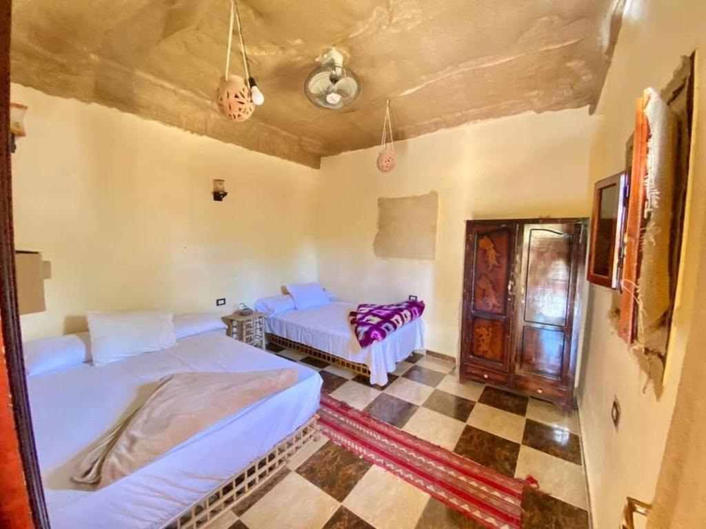 1 dormitorio con 2 camas y suelo a cuadros en غزاله كامب en Siwa