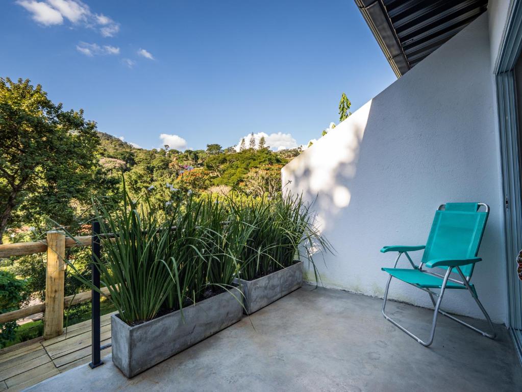 a green chair sitting on a patio with plants at Green Loft - ITAIPAVA in Petrópolis